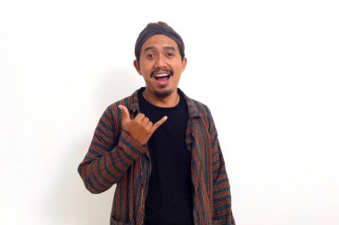 Geleneksel jakuzi kostümlü mutlu Asyalı adam Shaka el hareketleriyle ayakta duruyor.