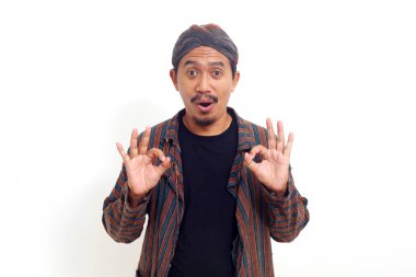 Mutlu Asyalı adam elinde iyi bir jest ile ayakta duruyor. Beyaz arkaplanda izole