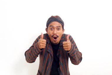 Heyecan verici Asyalı adam ayakta ve iki eliyle baş parmağını kaldırıyor. Beyaz arkaplanda izole