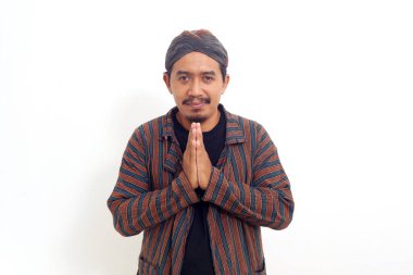 Dost canlısı Asyalı adam karşılama jestiyle ayakta duruyor. Beyazda izole edilmiş