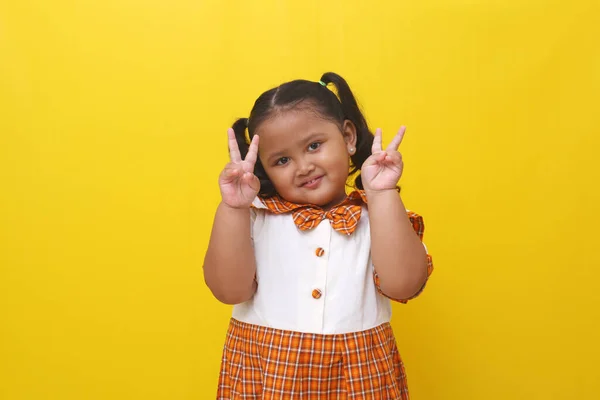 Asian Little Schoolgirl Standing While Showing Victory Finger Hand Gesture — Zdjęcie stockowe