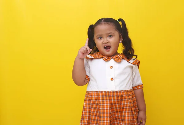 Asyalı Küçük Kız Tek Parmağını Gösterirken Ayakta Duruyor Sarı Arkaplanda — Stok fotoğraf