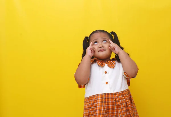 Asyalı Küçük Kız Bir Şey Düşünürken Ayakta Duruyor Sarı Arkaplanda — Stok fotoğraf