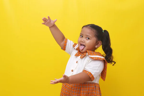 Asian Little Schoolgirl Standing While Presenting Something Isolated Yellow Background — Φωτογραφία Αρχείου