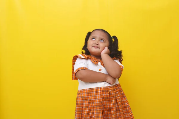 Asian Little Schoolgirl Standing While Thinking Something Isolated Yellow Background — стоковое фото