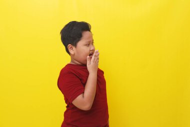 Wow and amazed expression of asian boy. Advertisement concept. Isolated on yellow background