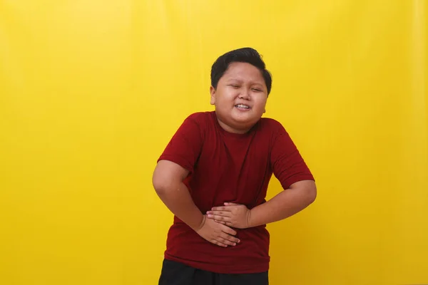 Asian Boy Standing Holding Stomach Feeling Hungry Isolated Yellow Background — Φωτογραφία Αρχείου