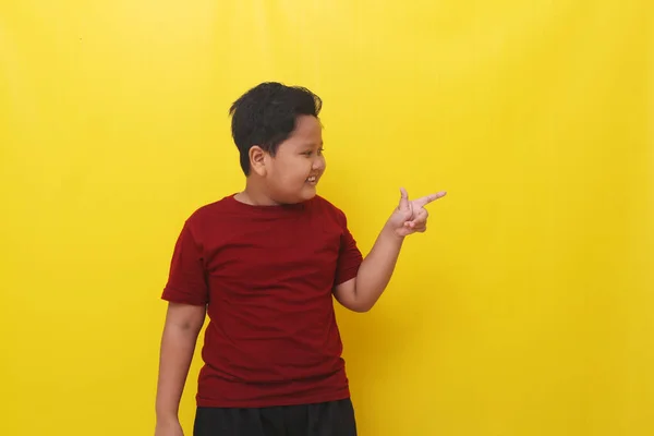 Happy Asian Boy Standing While Pointing Empty Space Isolated Yellow — Foto de Stock
