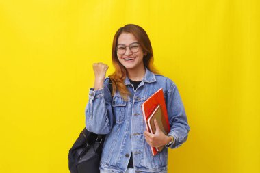 Başarılı genç Asyalı üniversite öğrencisi kitap tutarken ve elini sıkarken ayakta duruyor..