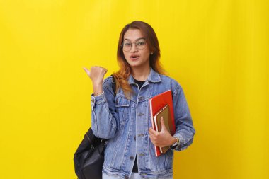 Asyalı genç bir üniversite öğrencisi kitap tutarken ve yandan bir şeyler sunarken...