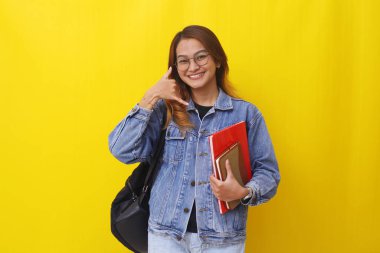 Genç Asyalı üniversite öğrencisi el hareketleriyle kitapları tutarken