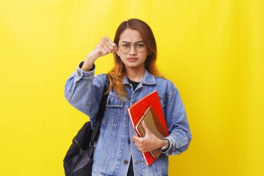 Öfkeli ya da Asyalı genç üniversite öğrencisinin portresi. Sarı arkaplanda izole edilmiş