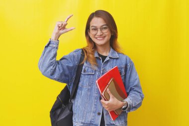 Güzel Asyalı üniversite öğrencisi, elinde C harfiyle kitap tutarken.