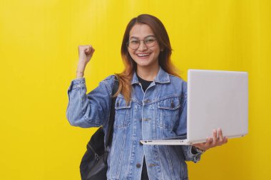 Başarılı genç Asyalı üniversite öğrencisi dizüstü bilgisayarını tutuyor ve elini sıkıyor.