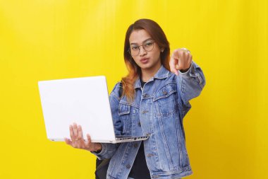 Elinde dizüstü bilgisayarla kamerayı işaret eden Asyalı genç üniversite öğrencisinin portresi.