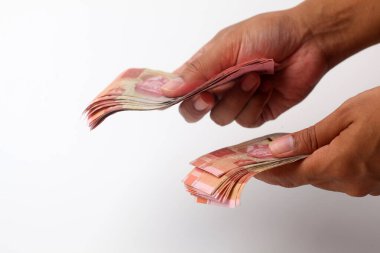 El ele tutuşup Endonezya parası veriyorlar. Beyaz arkaplanda izole