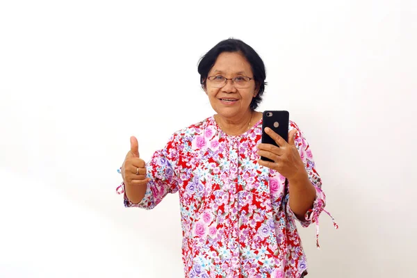 Ασιάτισσα Γριά Στέκεται Κρατώντας Ένα Κινητό Τηλέφωνο Και Δείχνει Τους — Φωτογραφία Αρχείου