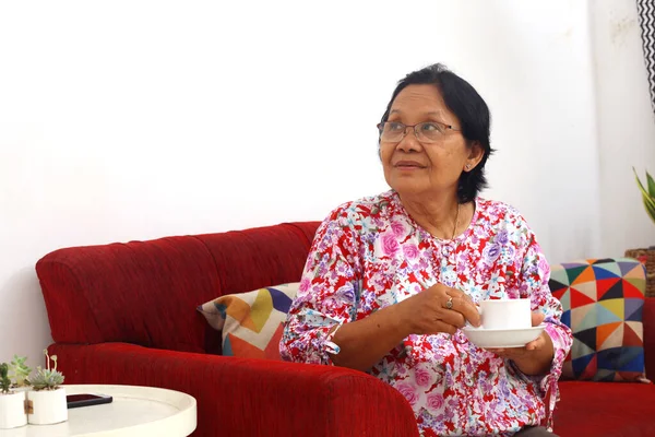 Ηλικιωμένη Ασιάτισσα Που Κάθεται Κρατώντας Ένα Φλιτζάνι Τσάι Και Σκέφτεται — Φωτογραφία Αρχείου