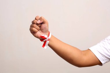 El 'in adamı, bileğinde kırmızı Whit kurdelesi olan Endonezya bayrağı tutuyor. Gri arkaplanda izole