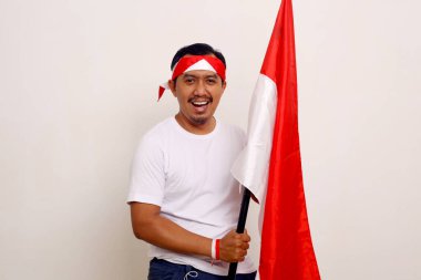Happy asian adult man standing while holding indonesian flag. Independence day concept. Isolated