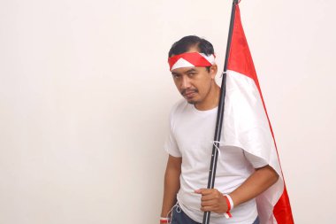 Asian man standing while holding indonesian flag. Independence day concept. Isolated on white