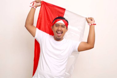 Endonezya bayrağı taşıyan mutlu Asyalı adam. Bağımsızlık Günü konsepti. Beyazda izole edilmiş