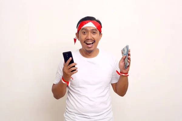 Happy Asian Man Standing While Holding Cellphone Indonesian Money Independence — 图库照片