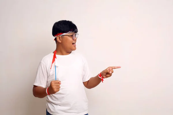 Aziatische Jongen Houdt Indonesische Vlag Terwijl Hij Zijwaarts Wijst Geïsoleerd — Stockfoto