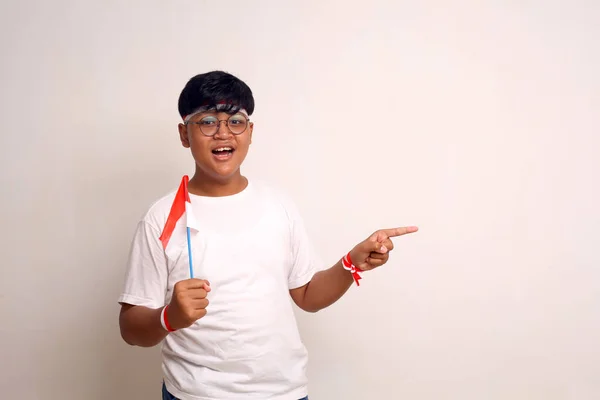 Ázsiai Fiú Indonéz Zászlót Tart Miközben Oldalra Mutat Fehér Alapon — Stock Fotó