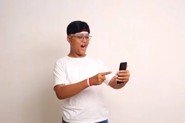 Amazed Asian Boy Standing While Holding Cell Phone Pointing Isolated — 图库照片