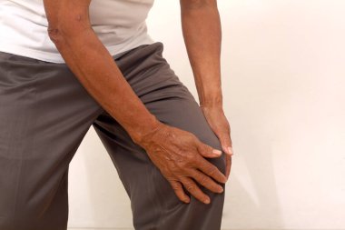 Close up photo of old man's hand holding his knee. Suffering from knee pain. Isolated on white