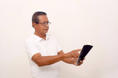 Elderly asian man standing while reading book. Isolated on white background