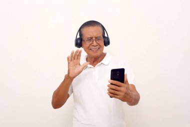 Happy asian old man standing while using his phone to video call. Isolated on white background