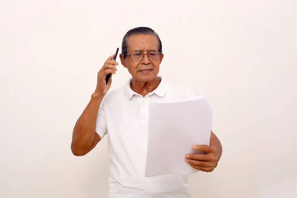 Elderly Asian Man Standing While Talking Phone Holding Papers Isolated — Zdjęcie stockowe