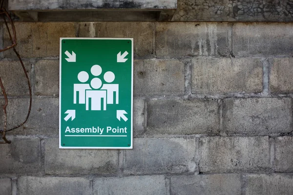 Assembly point sign on the wall. Emergency sign.