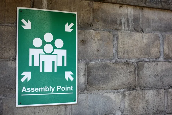 Assembly point sign on the wall. Emergency sign.