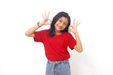 Adorable asian little girl standing while showing OK hand gesture. Isolated on white background