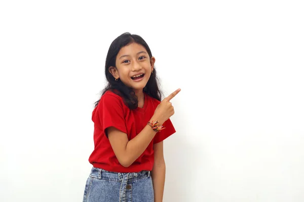 Happy Asian Little Girl Standing While Pointing Empty Space Isolated — Stockfoto