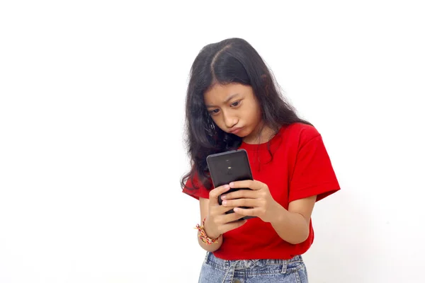 Frown Asian Little Girl Standing While Holding Cell Phone Isolated — Stok fotoğraf