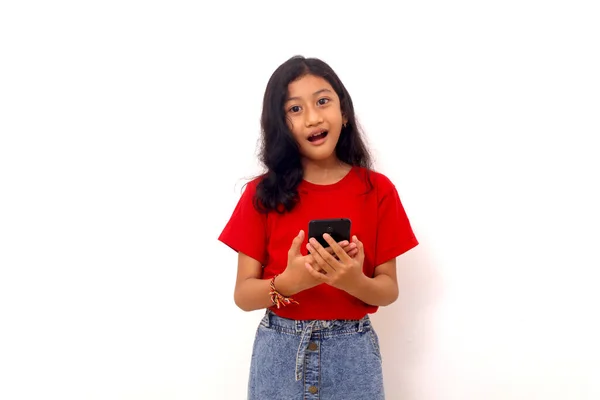 Amazed Asian Little Girl Standing While Holding Cell Phone Isolated — Fotografia de Stock