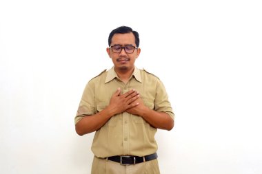 Relieved Indonesian government employees standing while holding chest. He feels peaceful