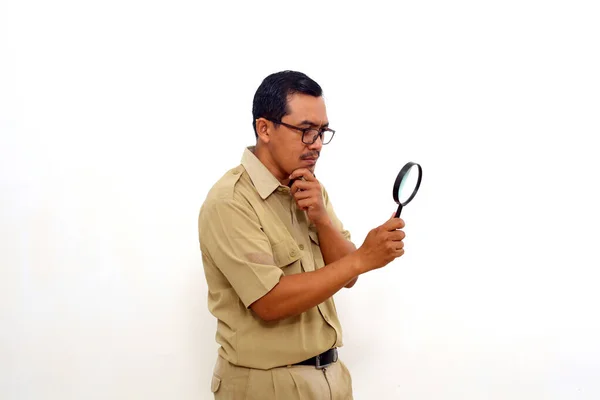 Curious Indonesian government employees standing while holding a magnifying glass. Isolated on white