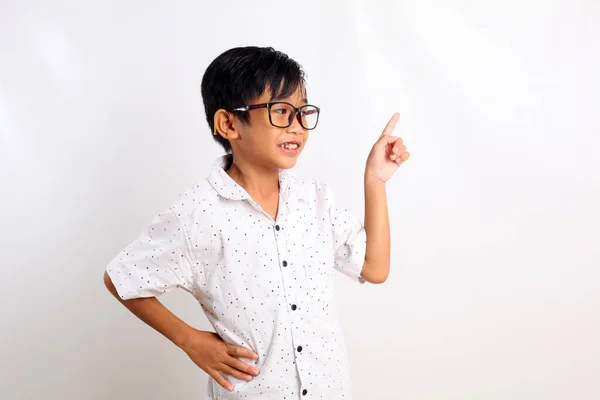 Happy asian boy standing while looking sideways and pointing something. Isolated on white background