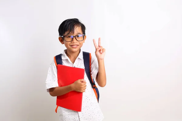 Happy Asian Schoolboy Standing While Showing Two Fingers Carrying Book — Stock Photo, Image