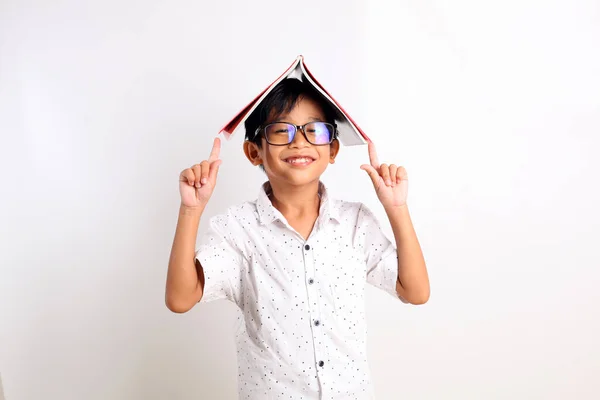 彼の頭の上に本を持つ幸せなアジアの少年 賢い学生の概念 白地に隔離された — ストック写真