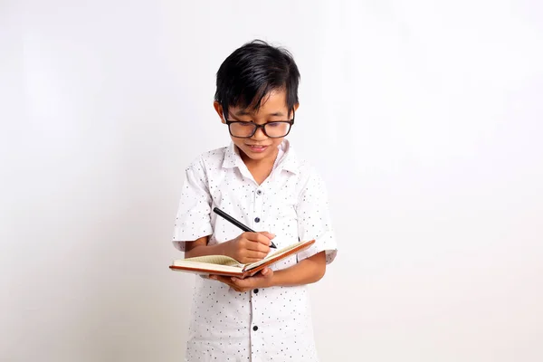 Έξυπνος Ασιάτης Μαθητής Στεκόταν Ενώ Έγραφε Στο Βιβλίο Απομονωμένο Λευκό — Φωτογραφία Αρχείου