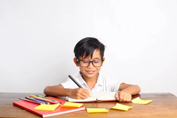 Veselý Asijský Školák Něco Píše Učebny Izolováno Bílém — Stock fotografie