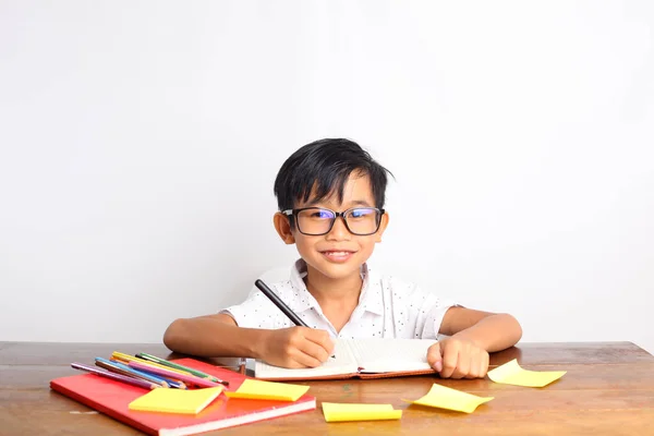 Happy Asian Schoolboy Writing Something Book Classroom While Looking Camera — Stock Photo, Image