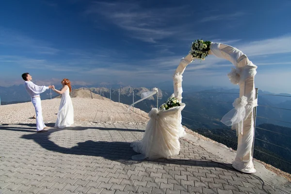 Os recém-casados posam perto do arco de casamento — Fotografia de Stock