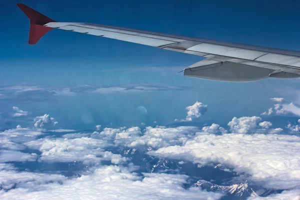 Montagne innevate e nuvole, la vista dall'alto con l'ala del pannello aereo — Foto Stock